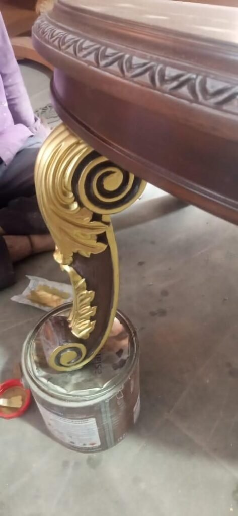 Artisan applying gold finish to a carved side table leg in the Morbagh workshop, made for the G20 Leaders Summit